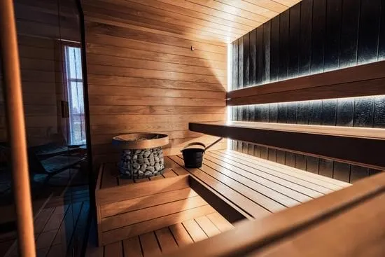Finnish sauna room with timber benches and softly glowing kiuas heater